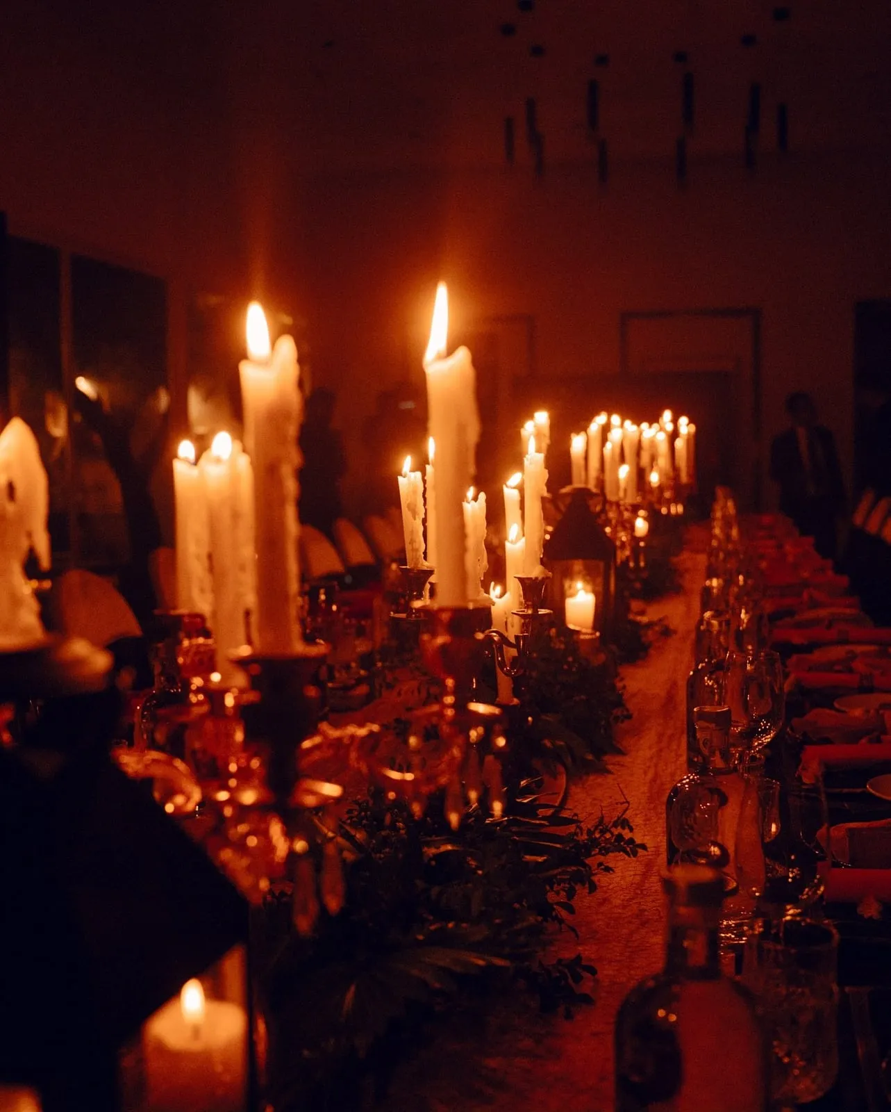 A candlelit communal dinner table set for Feast of Fire & Smoke