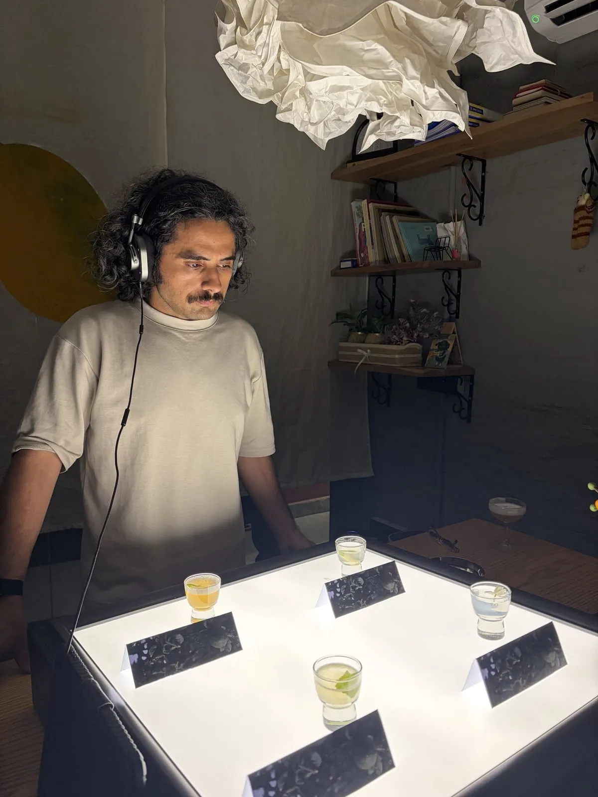 A guest in headphones leans over the backlit tasting table